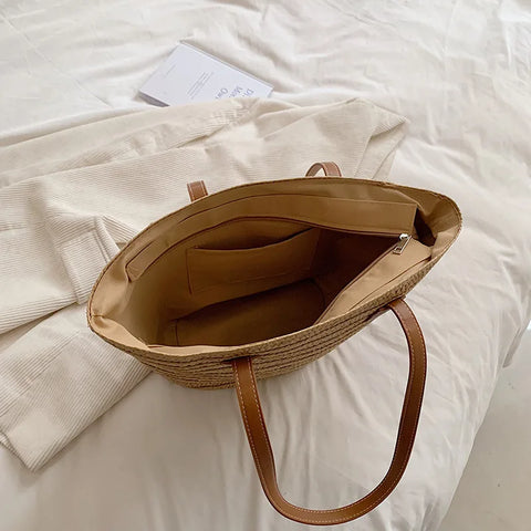 Inside of natural straw bag shows clean construction, tan lining, zipper closure and inner pocket