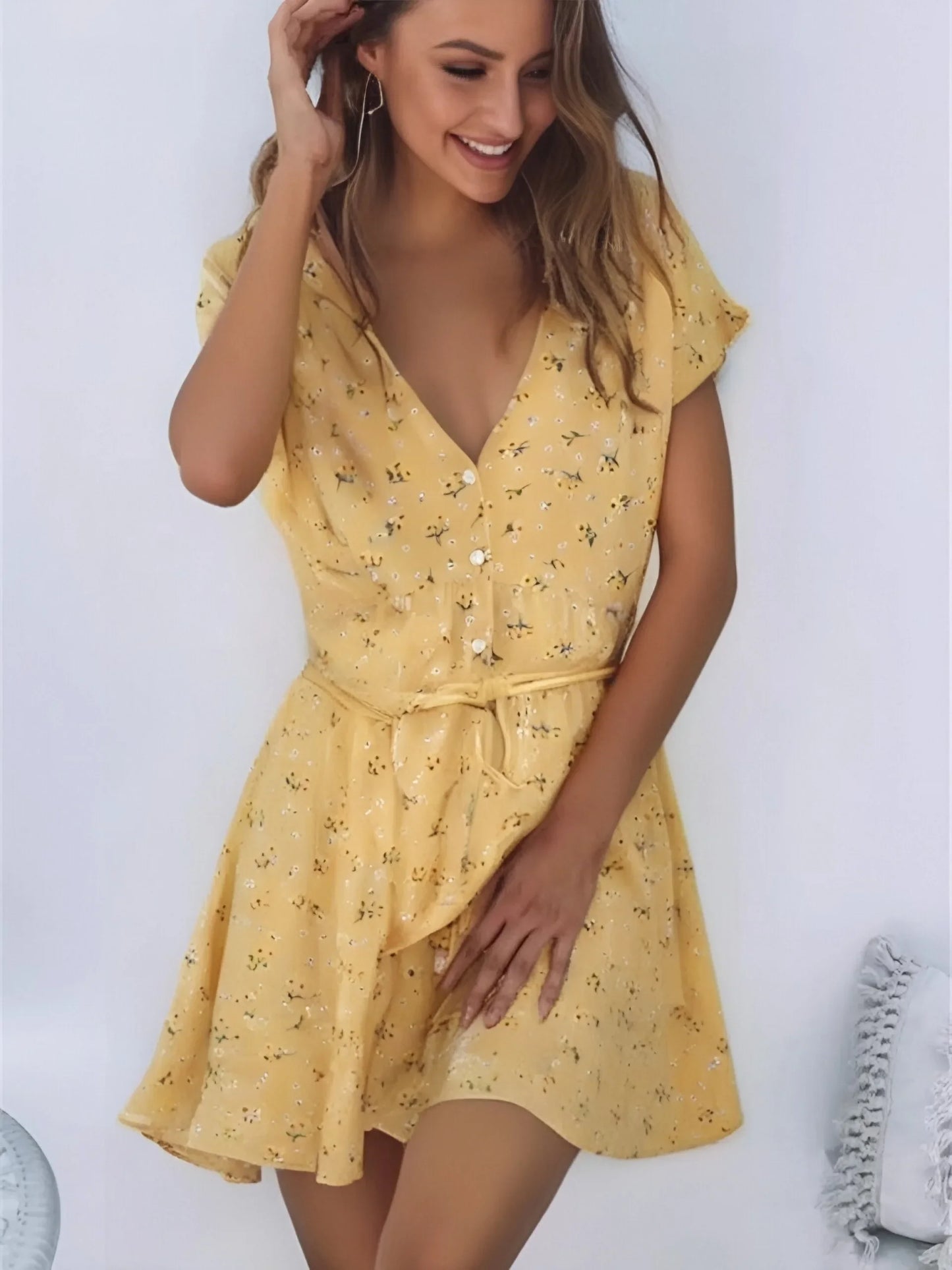 Nyla Flutter Mini Dress from Shop the Kei - flowing yellow and white floral top closes at the front with white buttons and sports a waist tie. Crafted with ruffles and made of natural fibers. Pairs with tan sandals