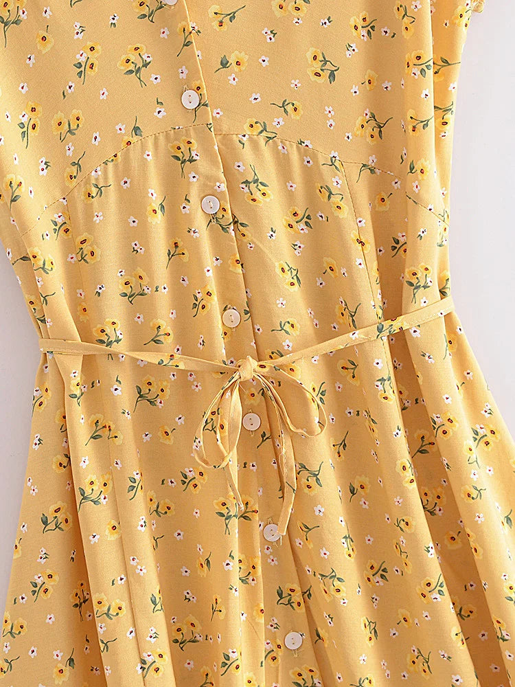 Nyla Flutter Mini Dress from Shop the Kei - close up of white button closure, waist seam, yellow and white floral pattern textile, and waist tie 