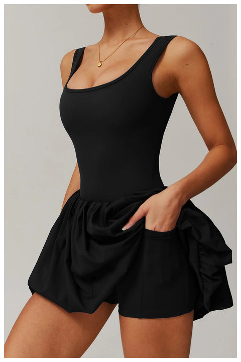 Side view of a model wearing the black Rinay Sport Dress from ShoptheKei activewear collection. Image reveals a pair of shorts sewn inside the dress and flat side pocket large enough for a phone or gym card.