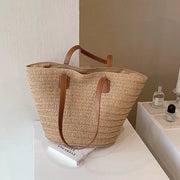 Natural tan color straw bag with tan lining, inner pocket, and brown faux leather straps 