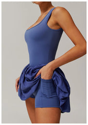 Side view of a model wearing the peri purple Rinay Sport Dress from ShoptheKei activewear collection. Image reveals a pair of shorts sewn inside the dress and flat side pocket large enough for a phone or gym card.