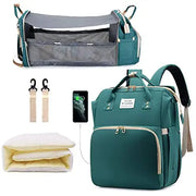 Green baby diaper backpack shown in multiple views: with additional straps, with USB charging port, folded mattress insert, and fully expanded as bassinet with mesh sides containing a baby. Lotus 3-in-1 bassinet diaper bag travel system with partial canopy