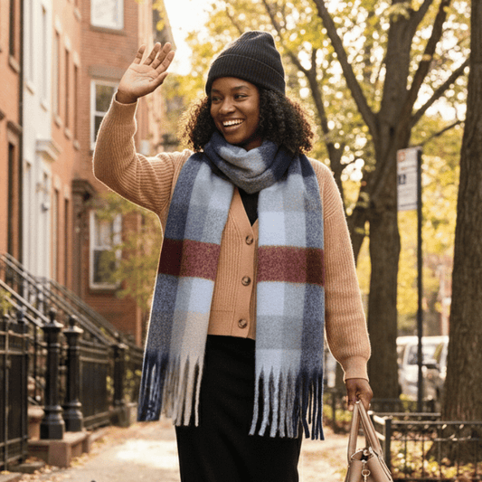 Woman wearing a Menswear Plaid scarf and beanie, standing on a street with trees and buildings in the background.