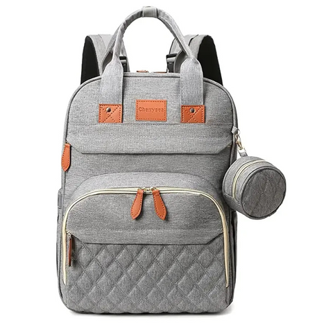 Gray Lotus 3-in-1 Bassinet Diaper Bag backpack with orange leather accents, featuring quilted front pocket, dual carry handles, and small circular accessory pouch. Full canopy available