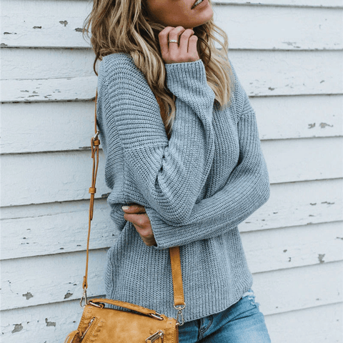 Close up front view of a model wearing gray colored Aries Sweater from Shop The Kei. The chunky knit sweater is styled with light blue jeans and a tan purse. Showcasing the sweater's chunky knit texture, soft relaxed fit, and versatile styling.